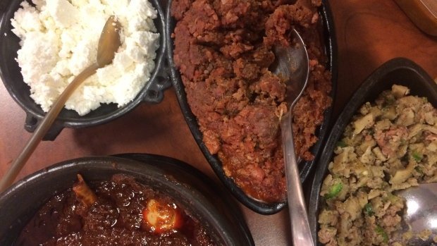 A dish often prepared at Ethiopian Orthodox Christmas, kitfo (centre, top) is a flavourful minced beef dish that's cooked with clarified butter and seasoned with cayenne pepper, cardamon, and salt. / CBC Photo 